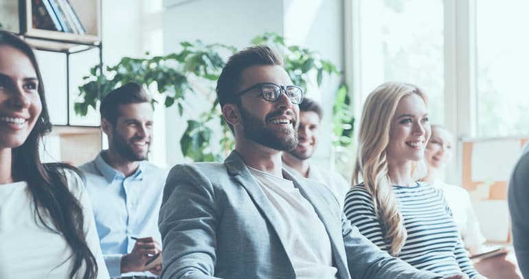 Group of employees sitting in a room listening to a presentation