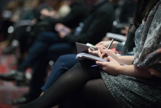 Close up people taking notes at a conference