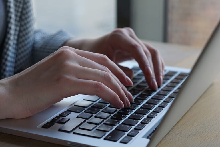 Close up of student's hands working at the computer to choose to take the PMP online or in person