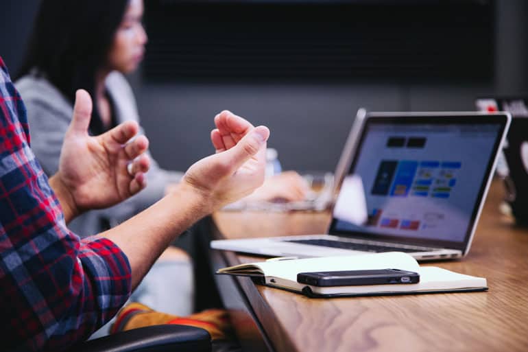 Close of a team member using hands to explain PMP exam benefits