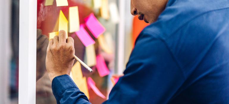 Project manager using the kanban methodology of sticky notes to track project tasks